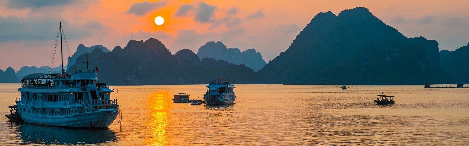 A group of boats are floating on top of a body of water at sunset.