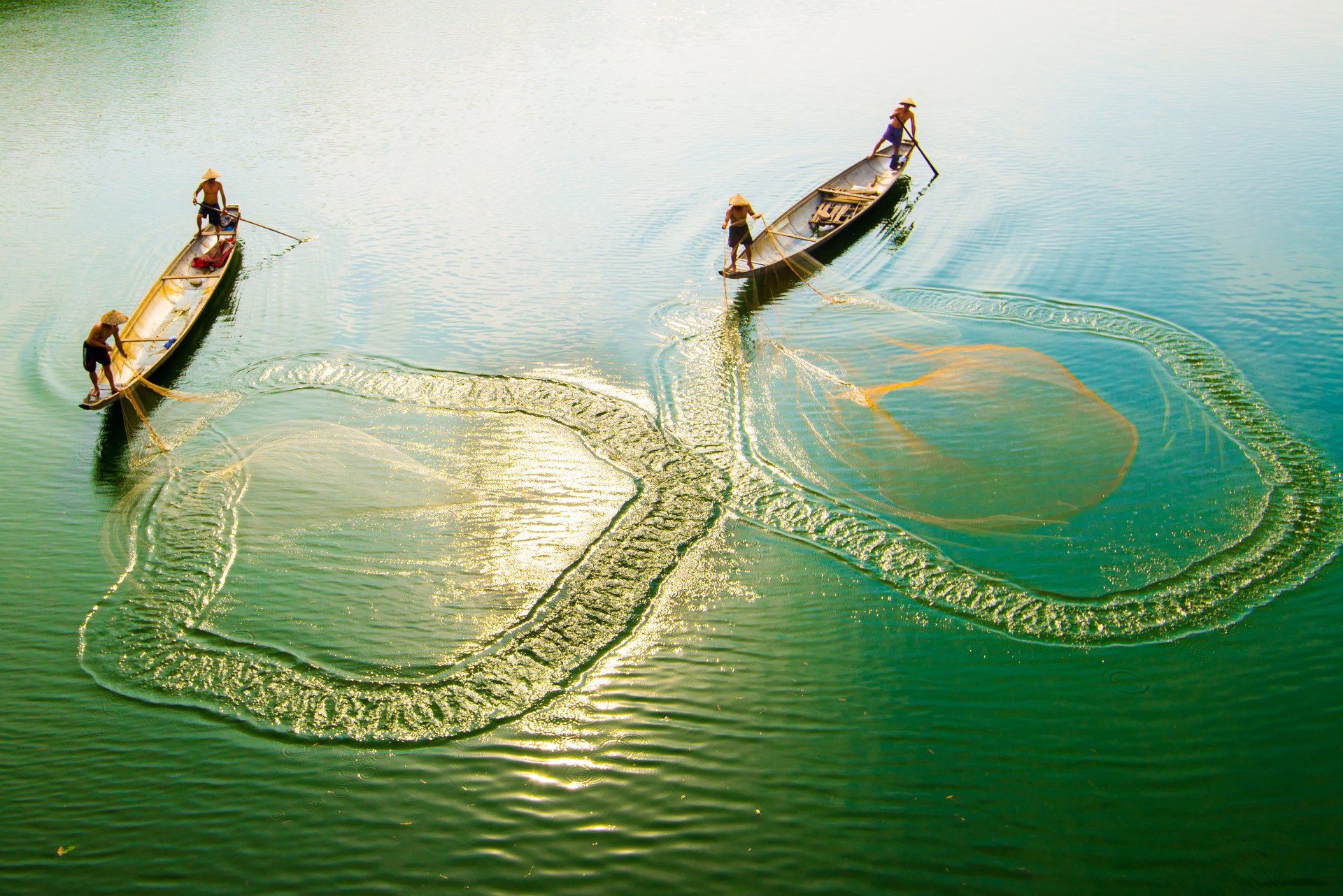 A couple of people in boats are fishing in a lake.