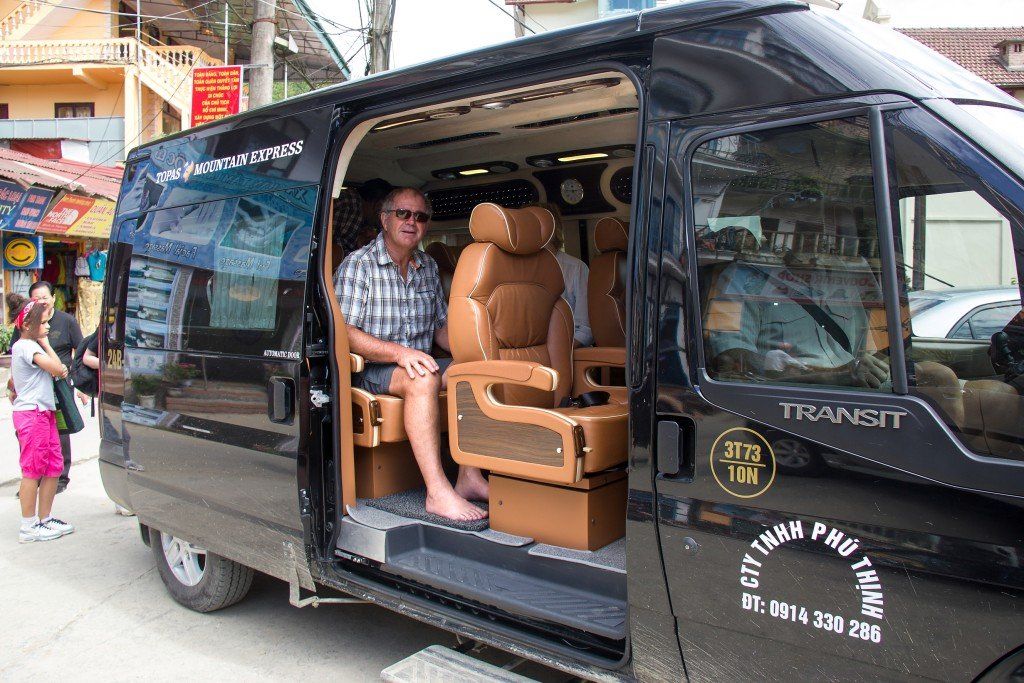 A man is sitting in the back seat of a black van.