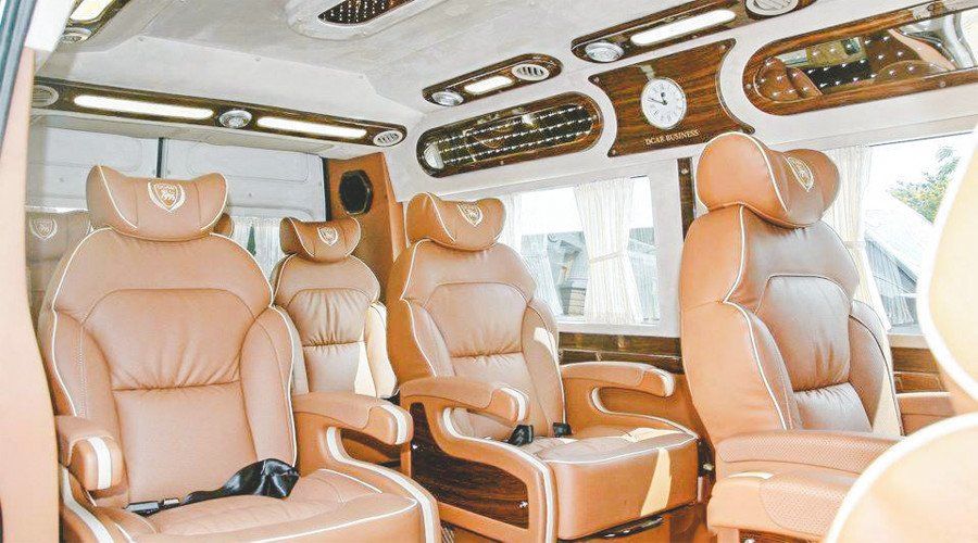The interior of a van with brown leather seats and a clock on the ceiling.