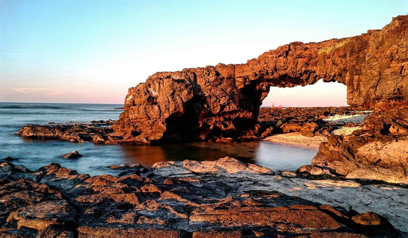 A large rock arch over a body of water