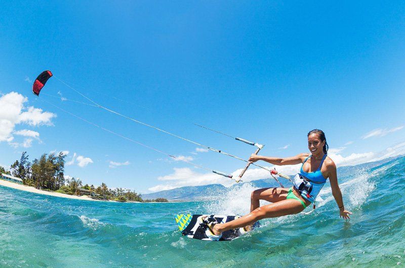 A woman is riding a wave on a kite board in the ocean.