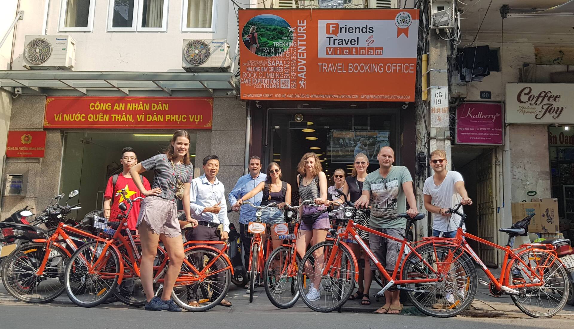 A group of people standing next to bicycles in front of a building.