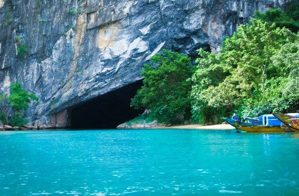 A boat is docked in front of a cave in the middle of a lake.