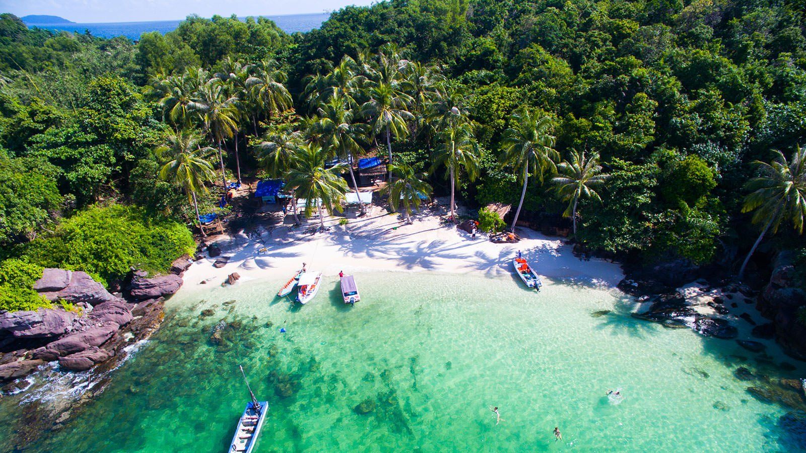 An aerial view of a tropical beach with boats in the water.