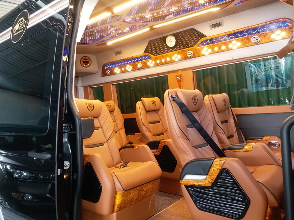 The inside of a van with leather seats and a clock on the ceiling.