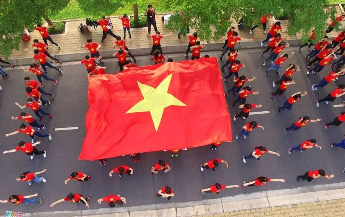 A group of people are holding a large red flag with a yellow star on it.