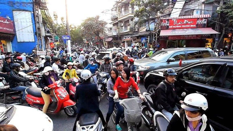 A crowd of people are riding scooters down a busy street.