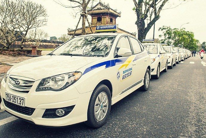 A row of white cars are parked on the side of the road.