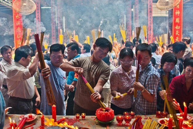 A group of people are standing around a table with candles and incense sticks.
