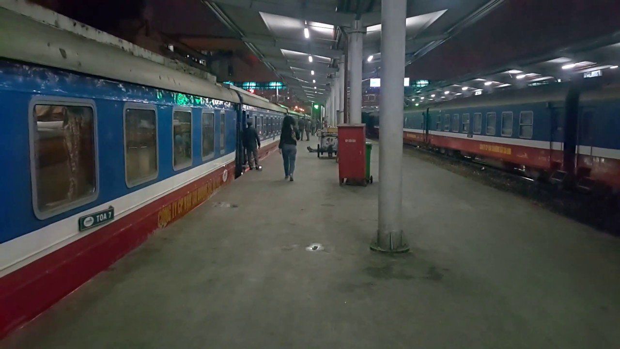 A woman is walking towards a train at a train station.
