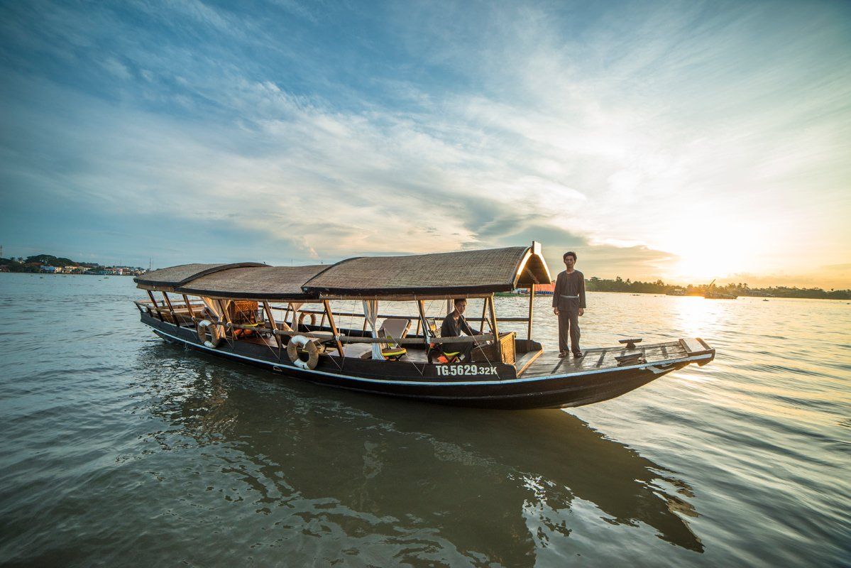 A man is standing on the deck of a boat in the water.