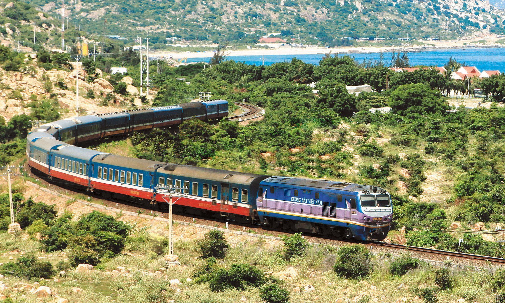 A train is going down the tracks in the middle of a forest.