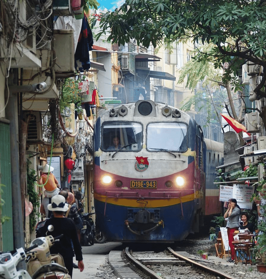 A train with a red flag on the front is going down the tracks
