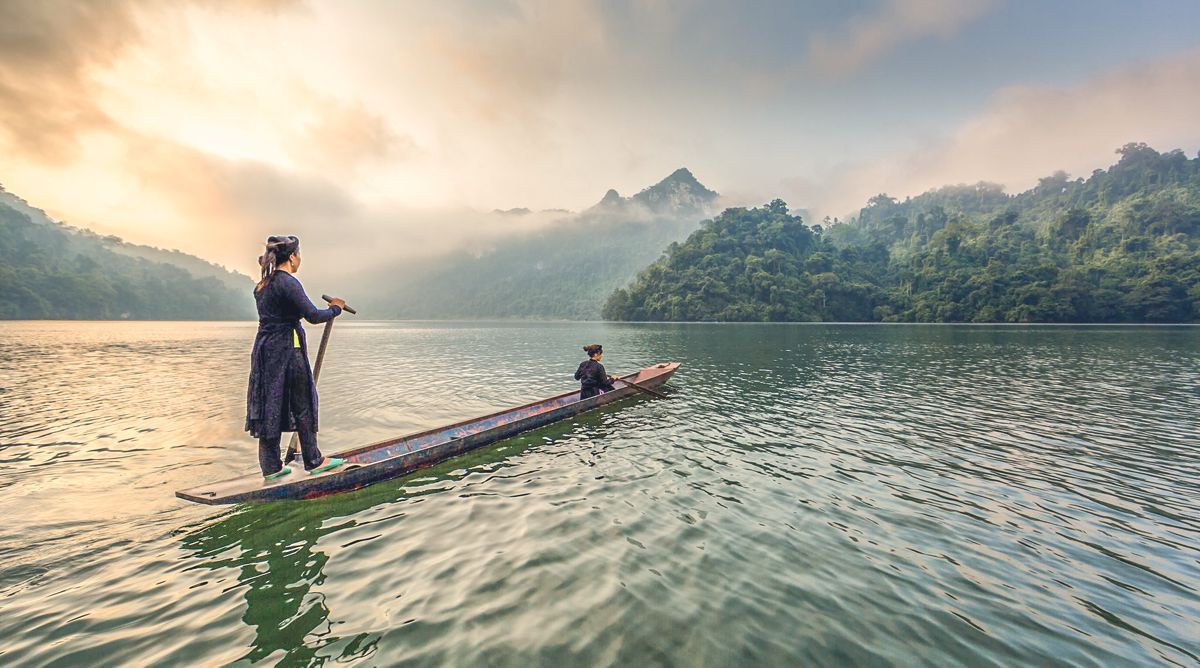 A man and a woman are rowing a boat on a lake.