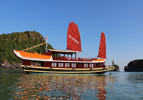 A boat with red sails is floating on top of a body of water.