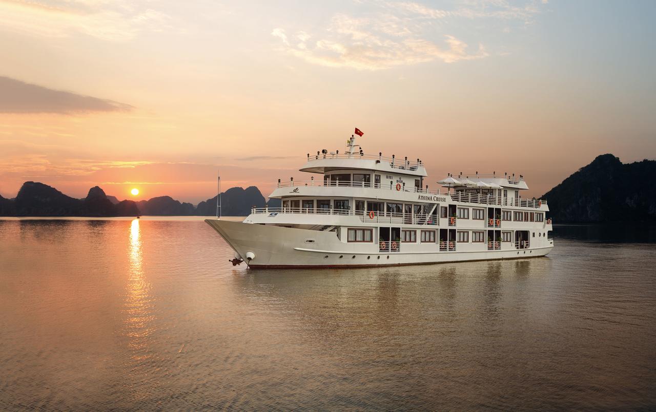 A large white boat is floating on top of a body of water at sunset.