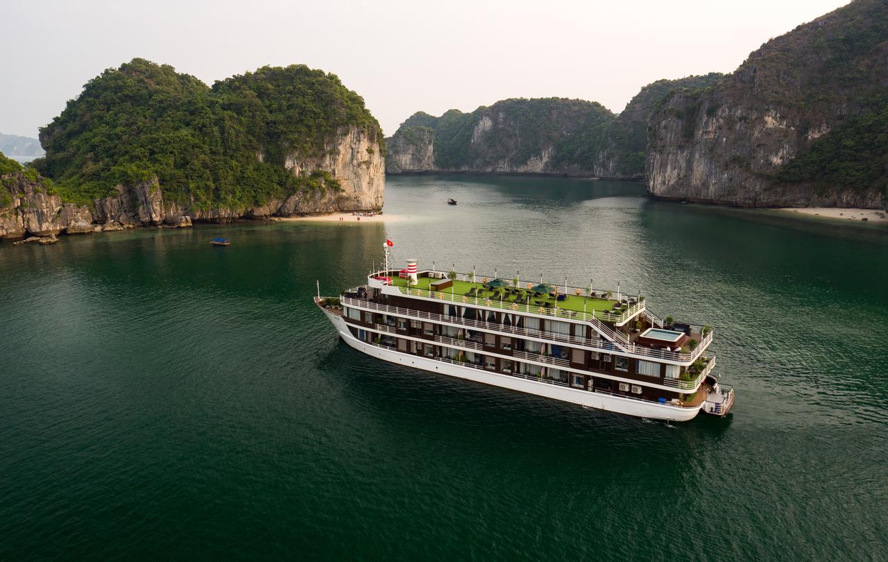 A large cruise ship is floating on top of a body of water surrounded by mountains.