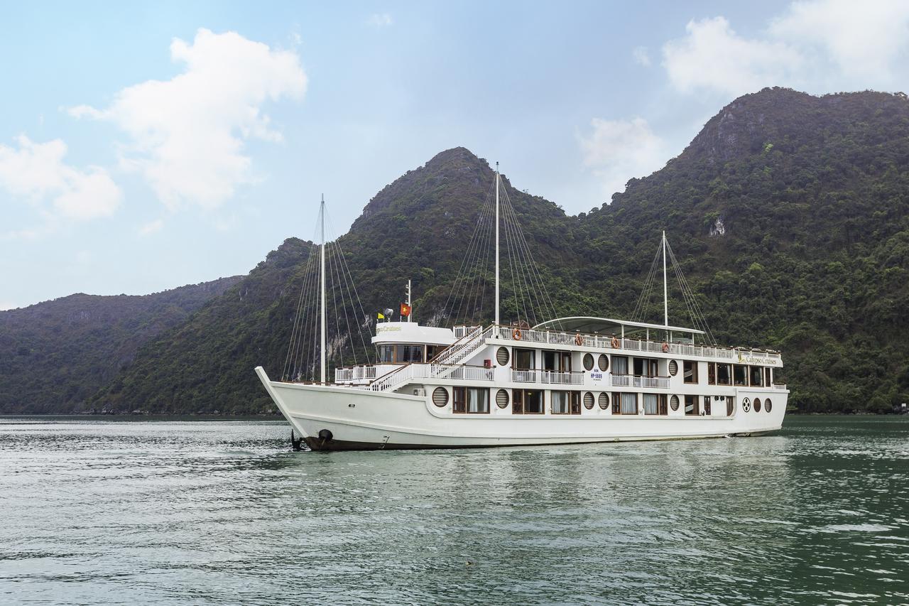 A large white boat is floating on top of a body of water with mountains in the background.