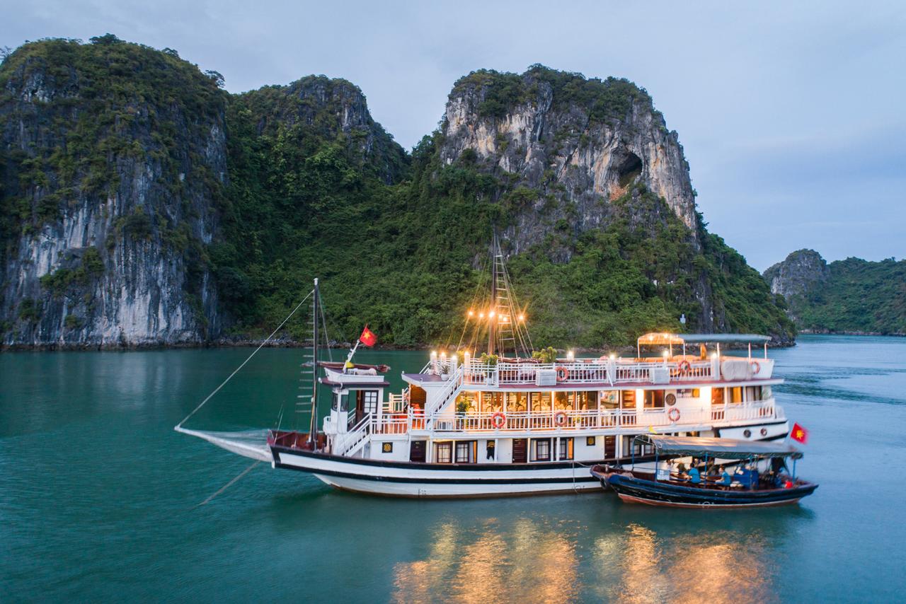 A large boat is floating on top of a body of water surrounded by mountains.