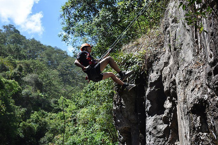 A man is climbing a rock wall with a rope.