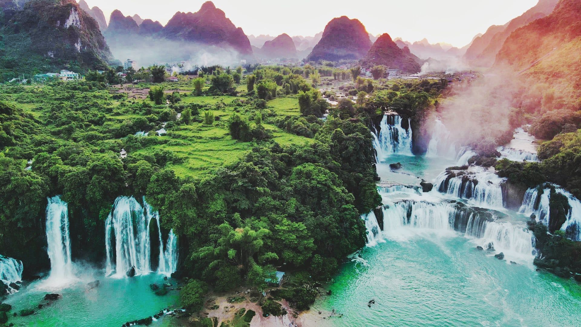 An aerial view of a waterfall in the middle of a river surrounded by trees.