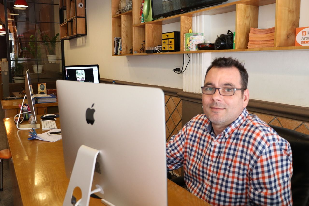 A man is sitting at a desk in front of an apple computer.