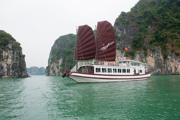 A boat with red sails is floating on top of a body of water.
