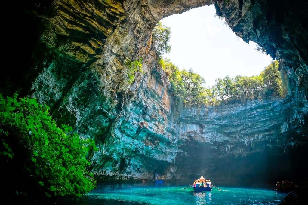 A boat is floating through a cave in the middle of a lake.