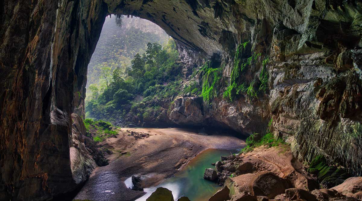 A large cave with a river coming out of it.