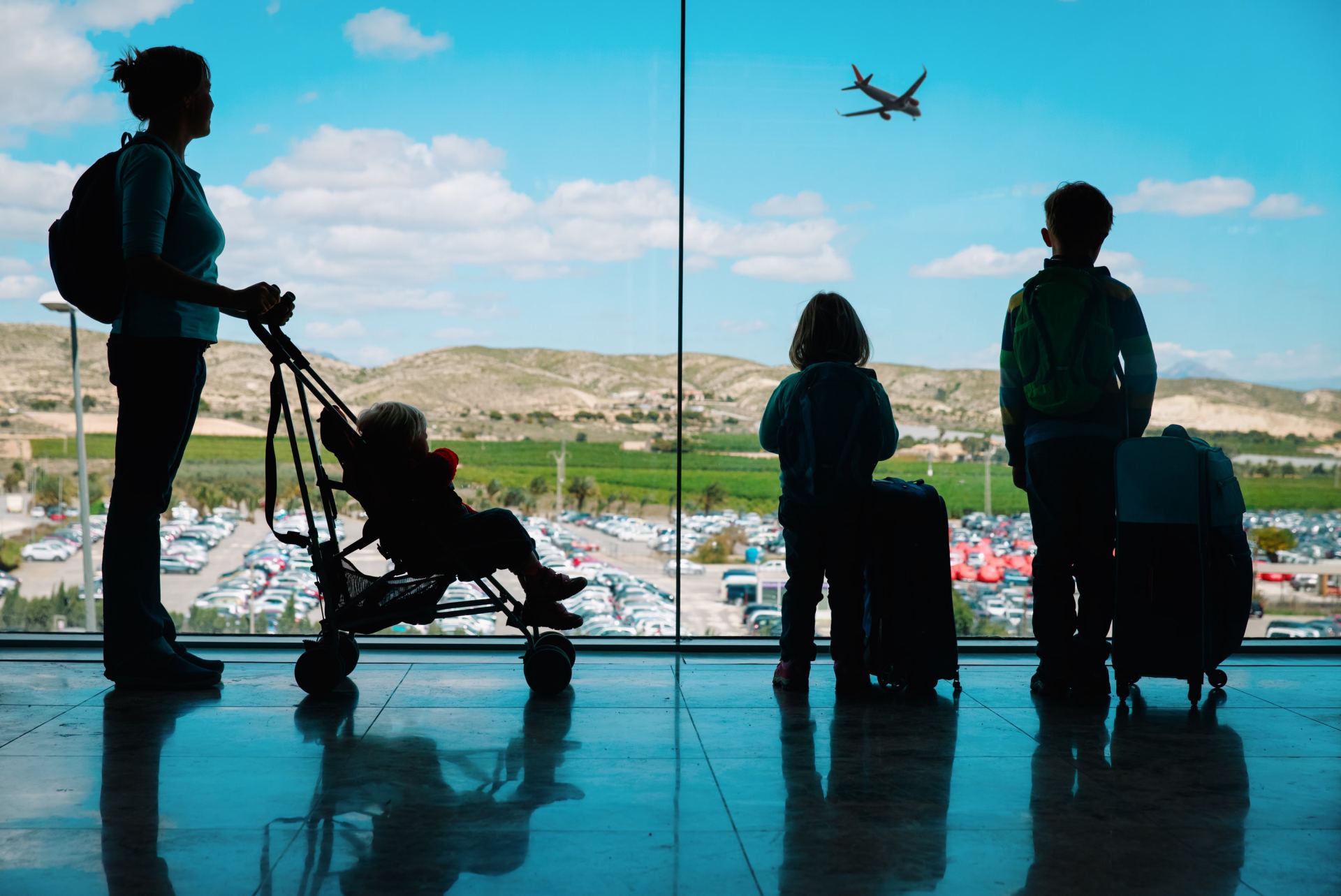 A family is looking out of a window at an airplane flying overhead.
