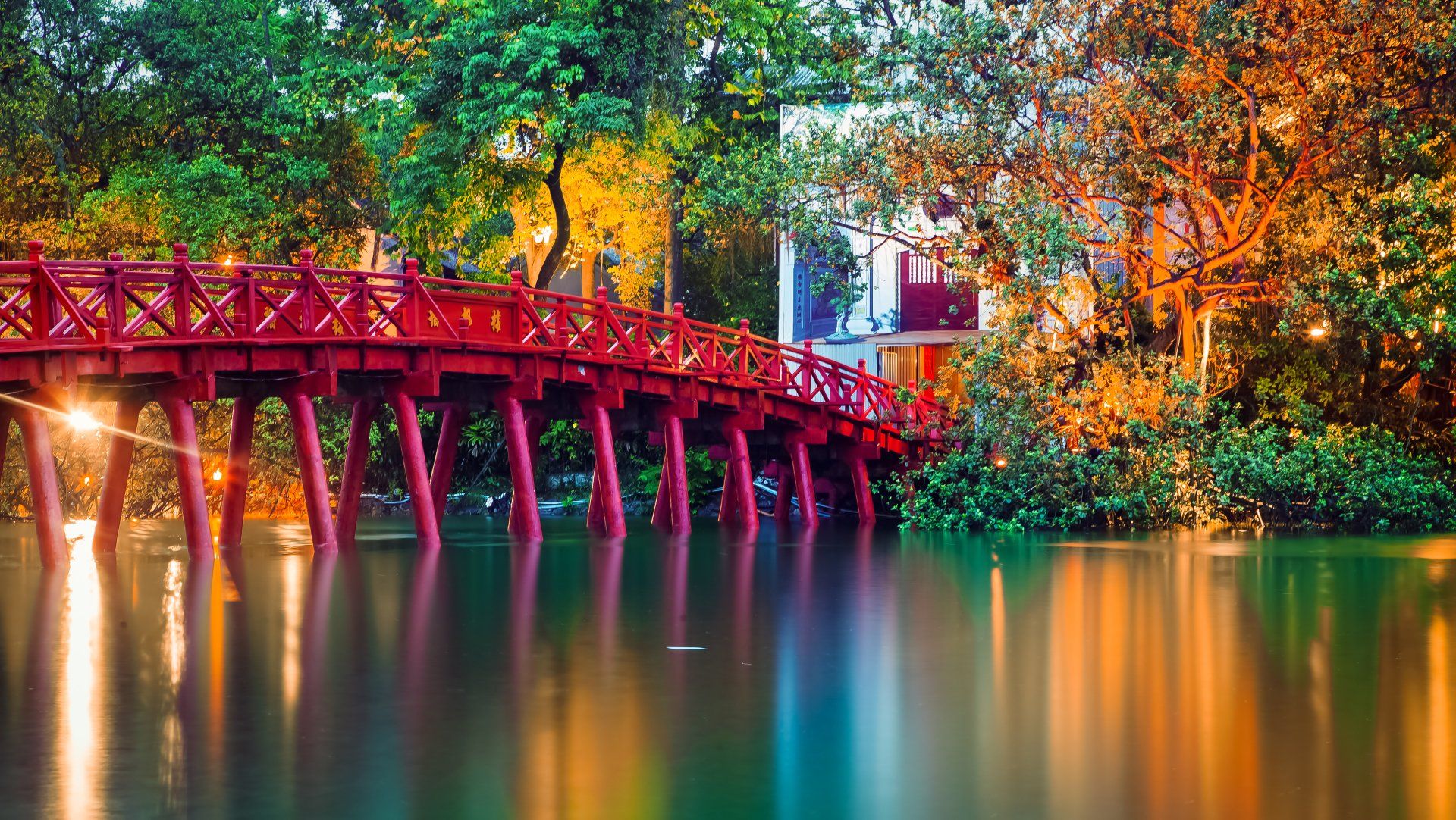 A red bridge over a lake with trees in the background.
