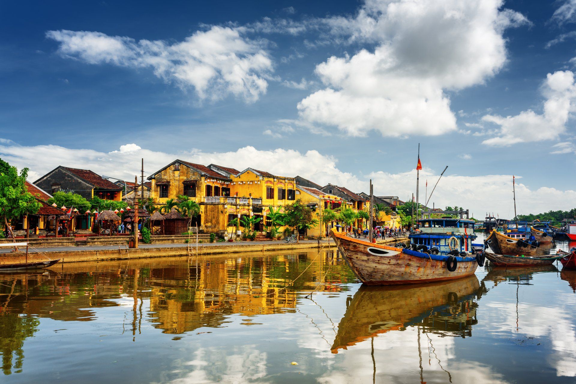 A group of boats are docked in a harbor with buildings in the background.
