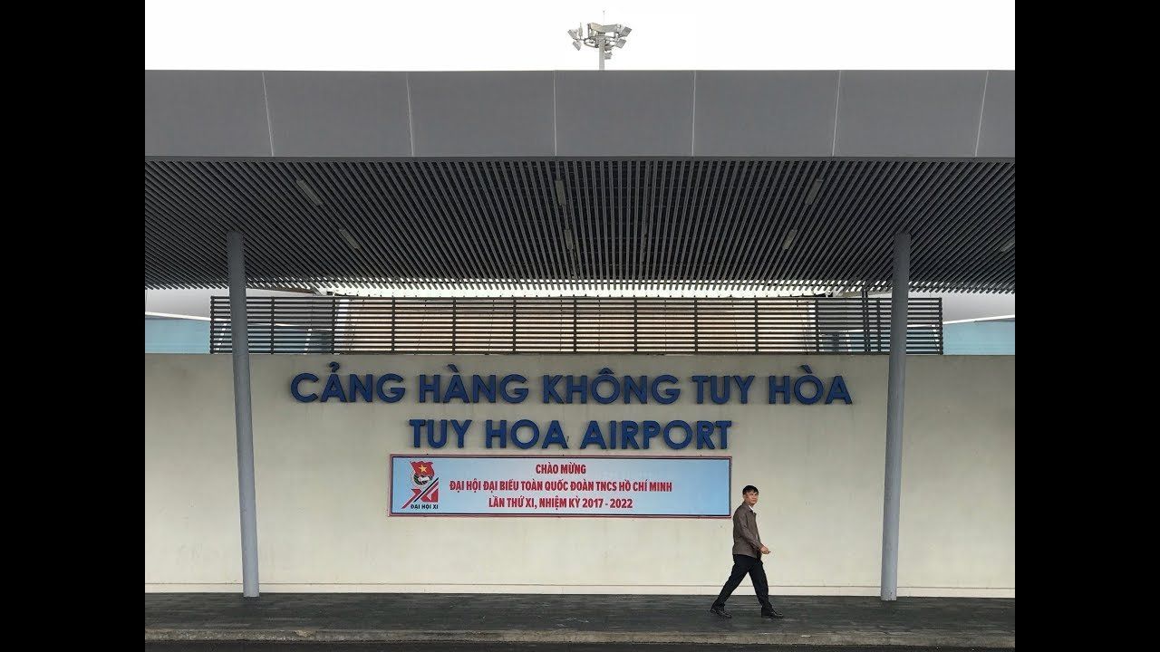 A man walks in front of a building that says tuy hoa airport