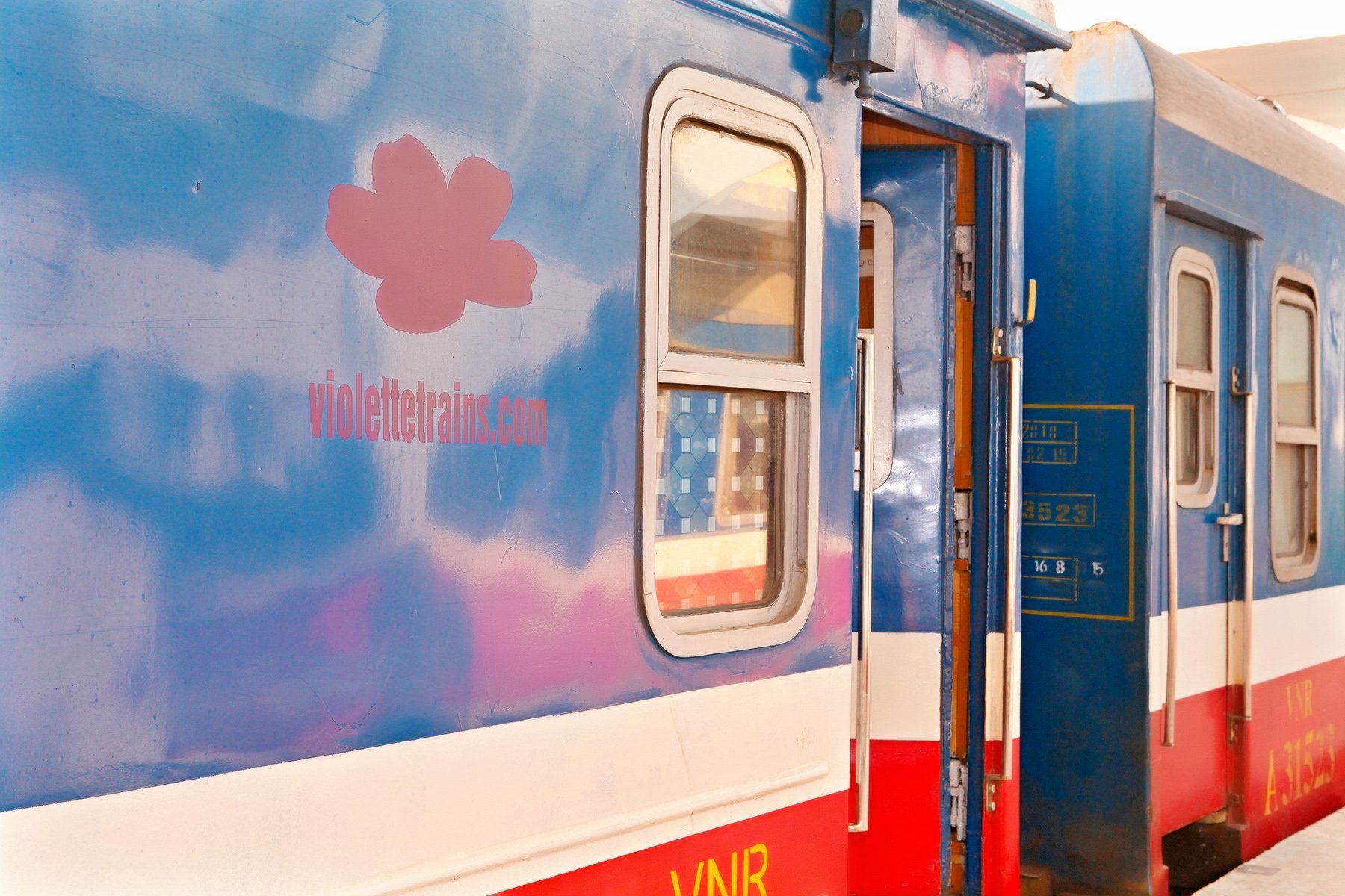 A blue and red train with a flower on the side