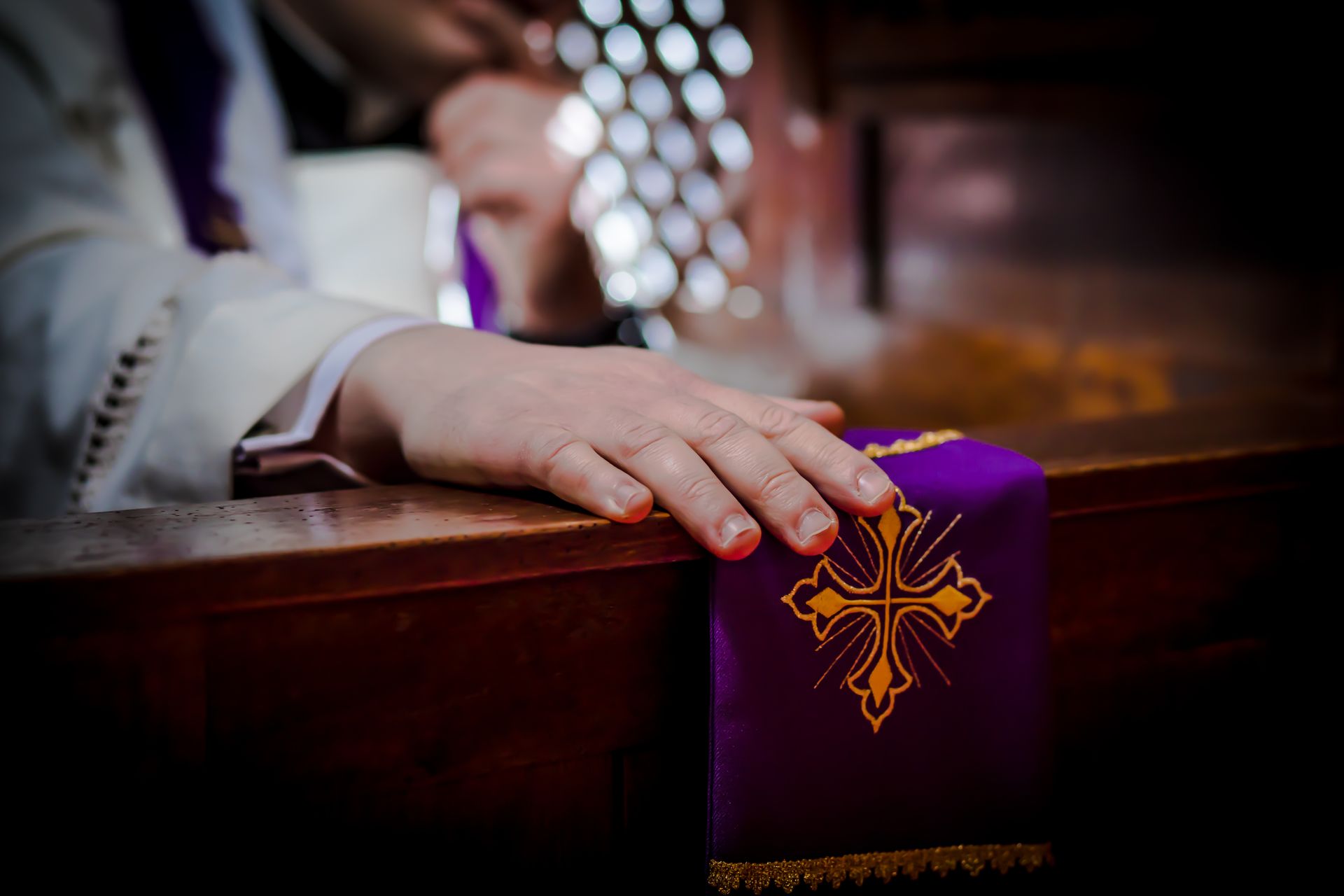 A person 's hand is resting on a purple cloth with a cross on it.