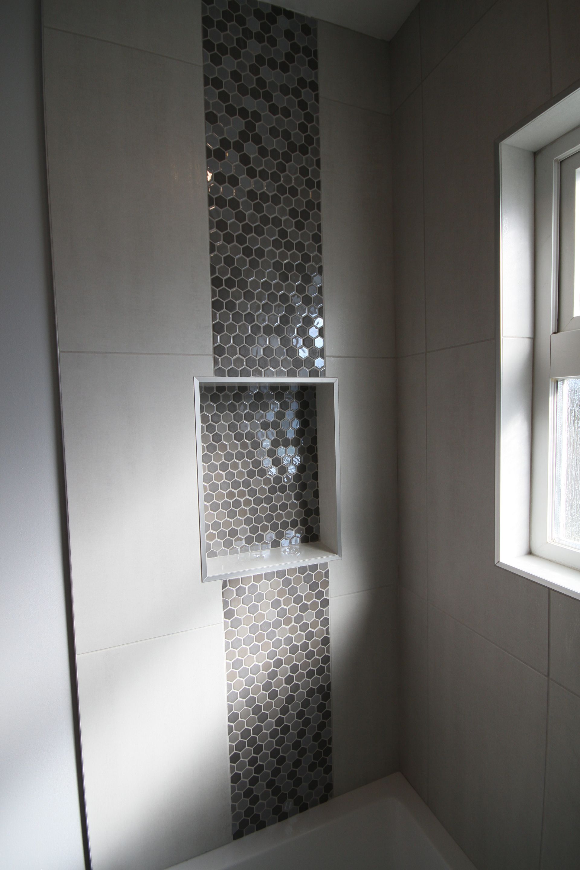 A bathroom with a window and a shelf in the wall.