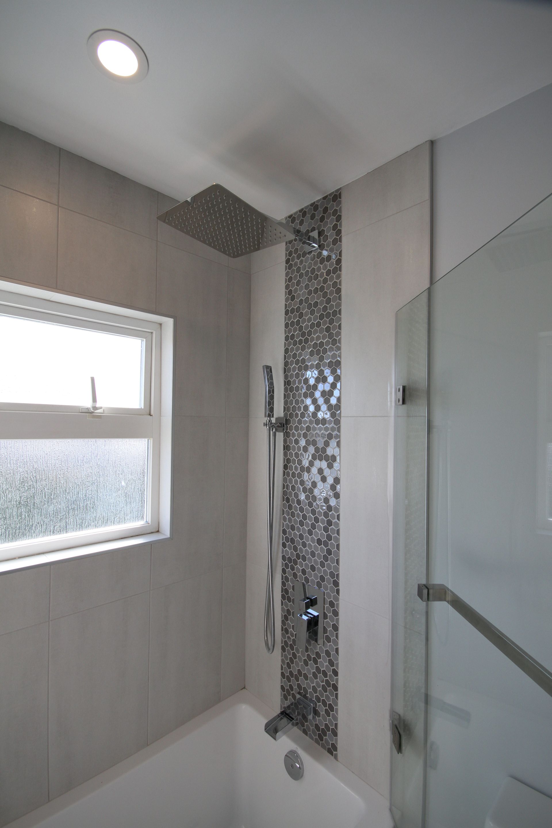A bathroom with a tub , shower , and window.