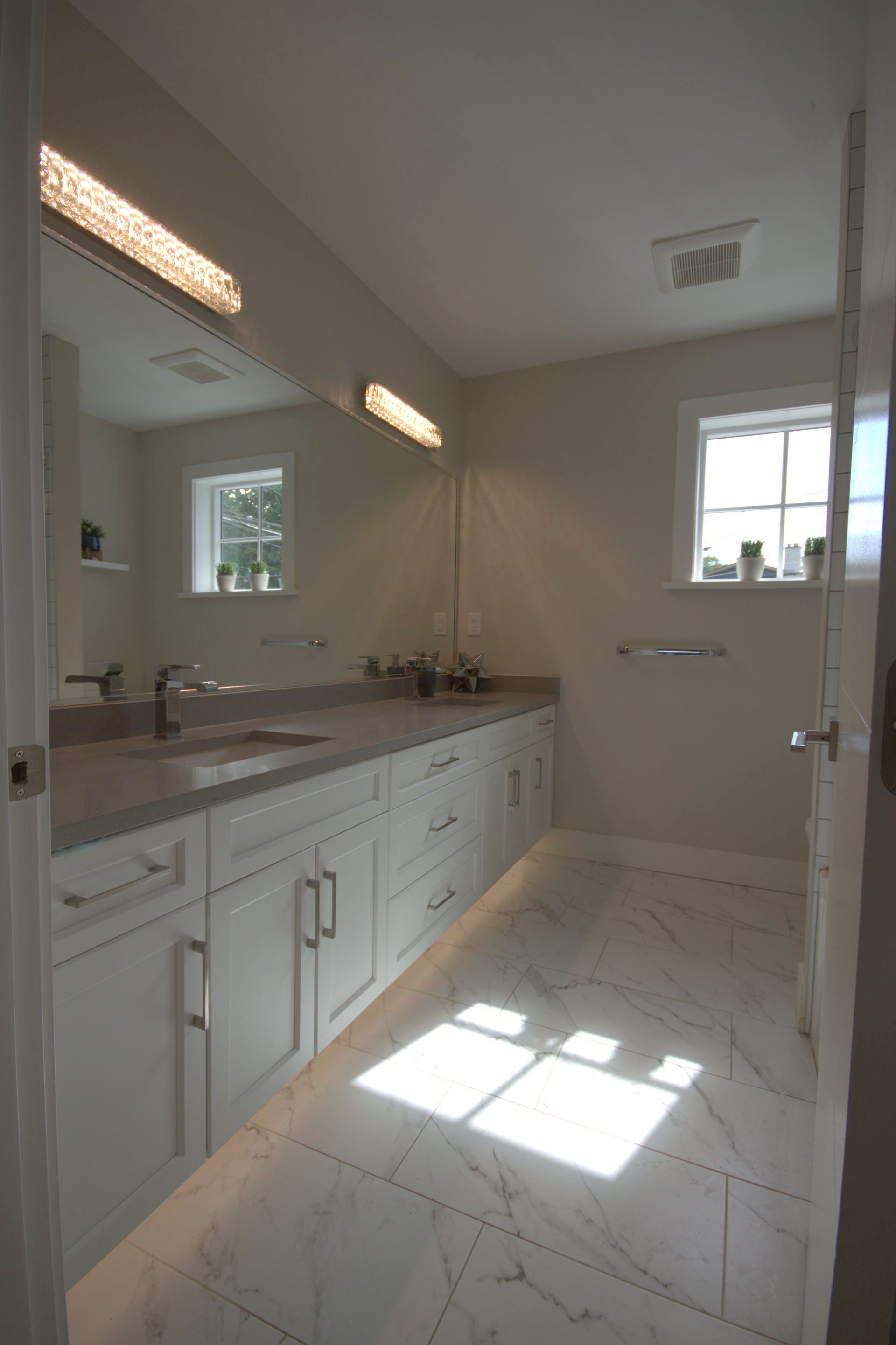 A bathroom with two sinks , a mirror and a window.