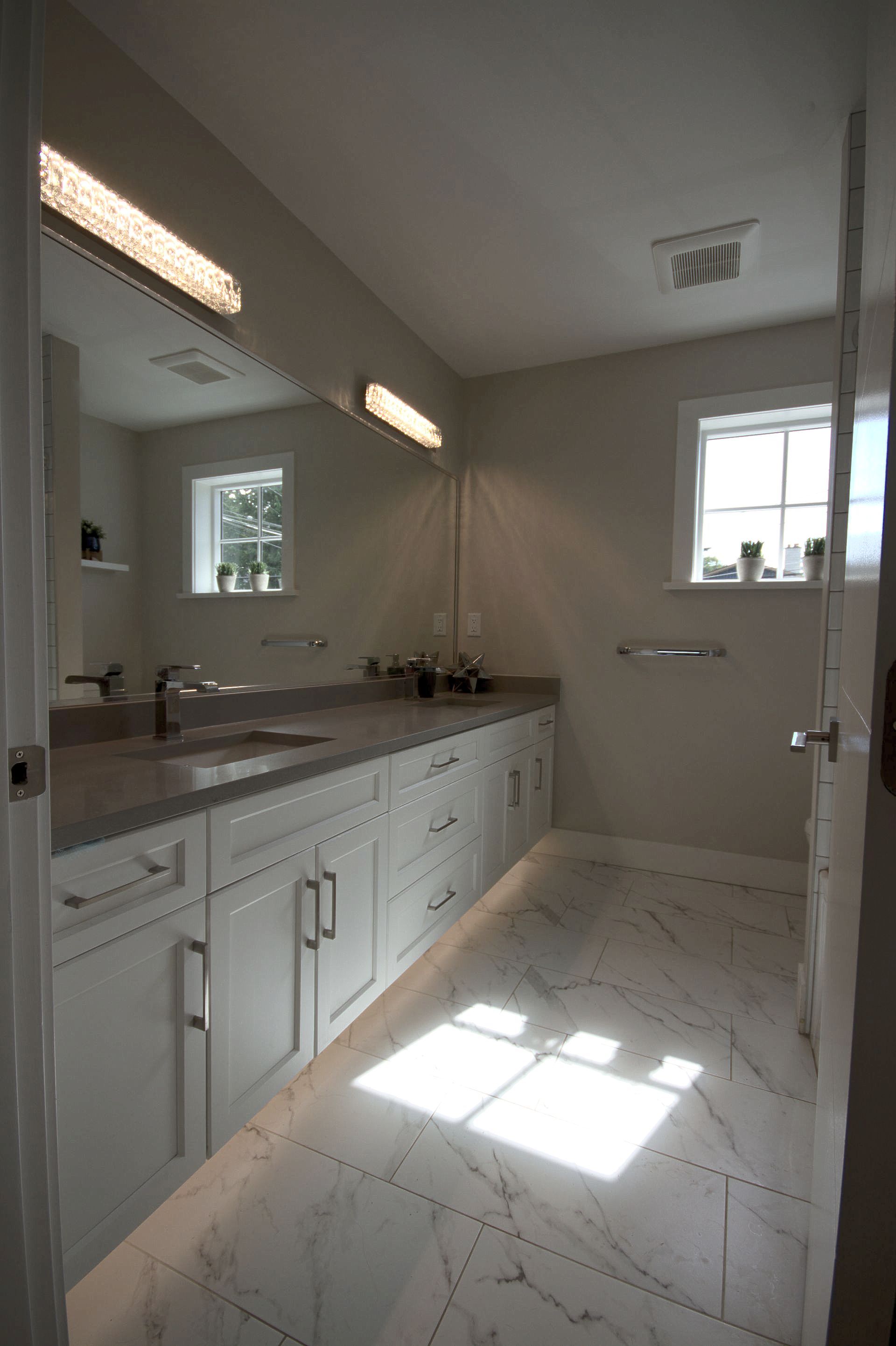 A bathroom with two sinks , a mirror and a window.