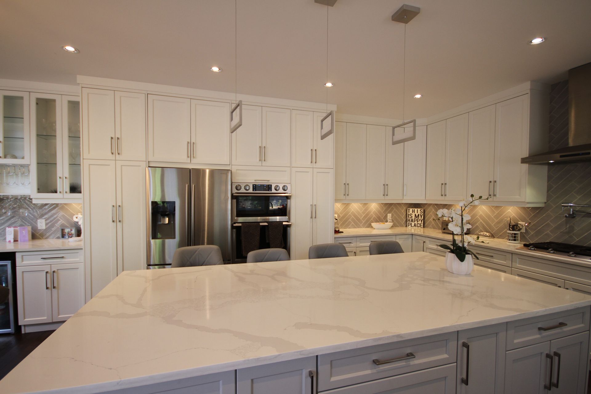 A kitchen with white cabinets , granite counter tops , stainless steel appliances and a large island.