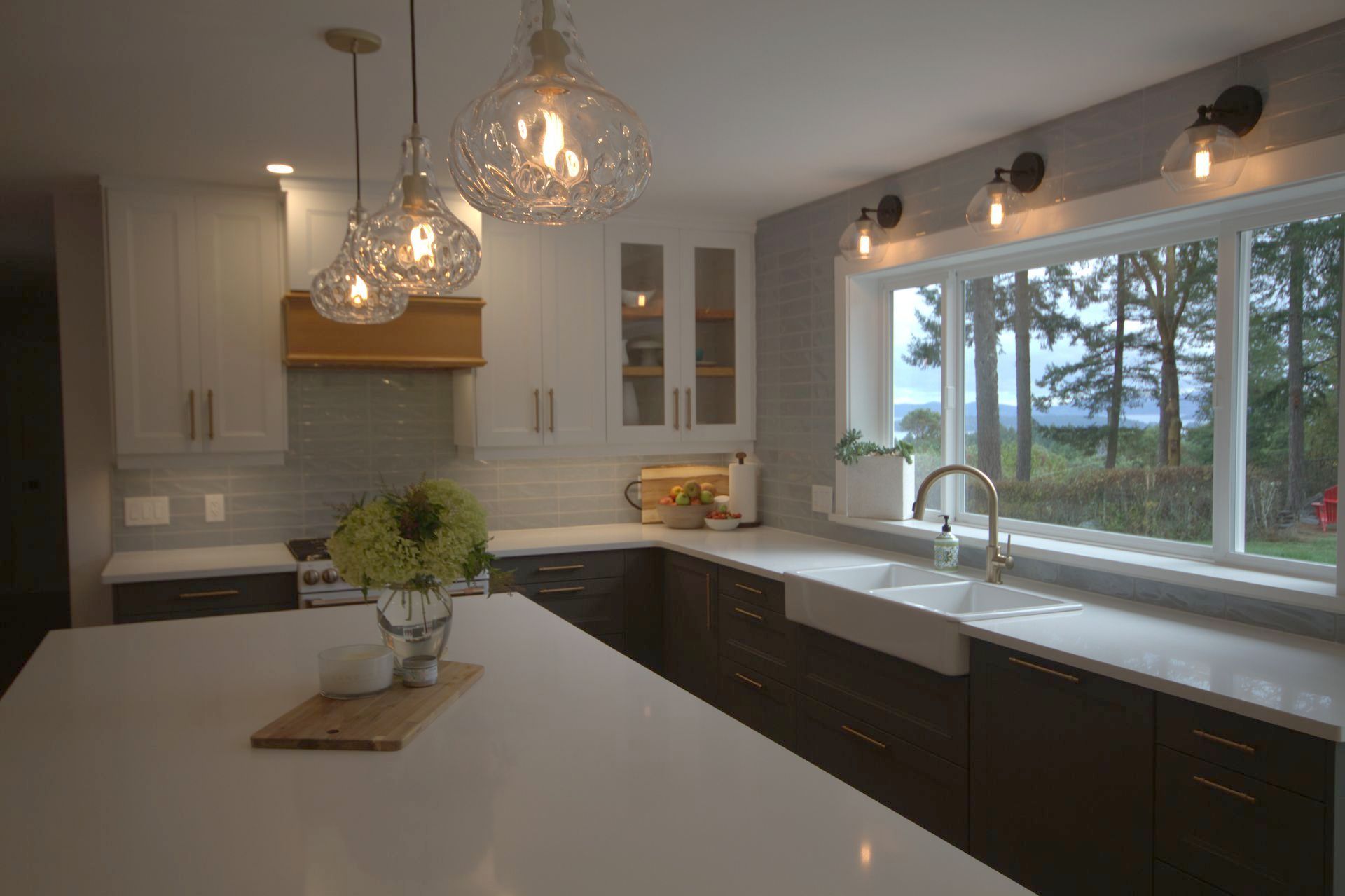 A kitchen with white cabinets , a sink , and a large window.