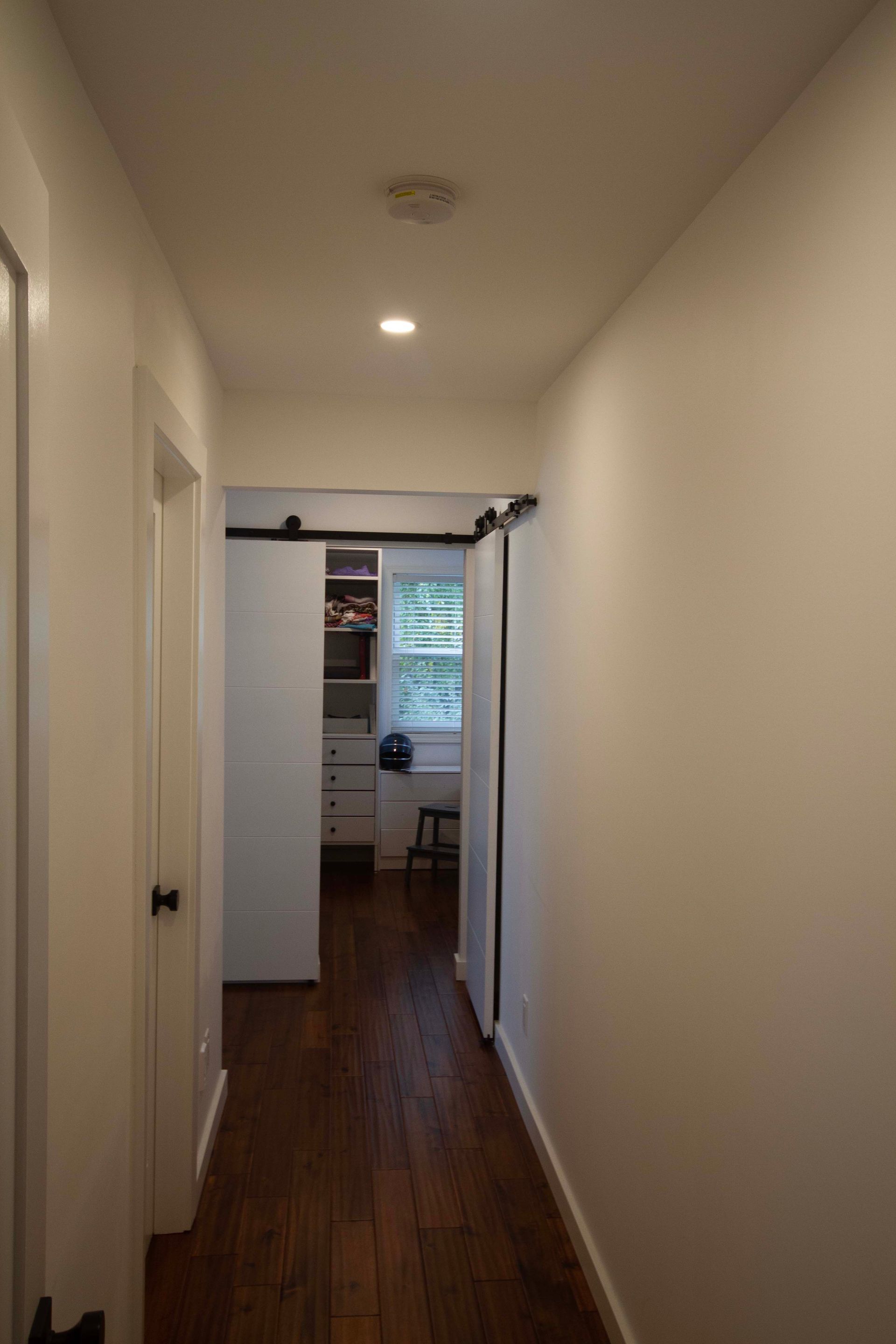 A long hallway with sliding barn doors leading to a kitchen.