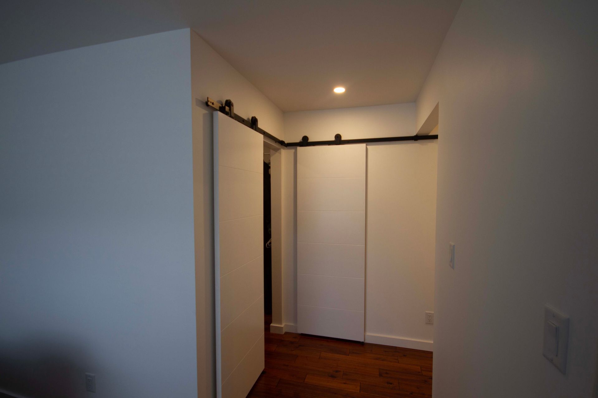 A hallway with sliding barn doors and a wooden floor