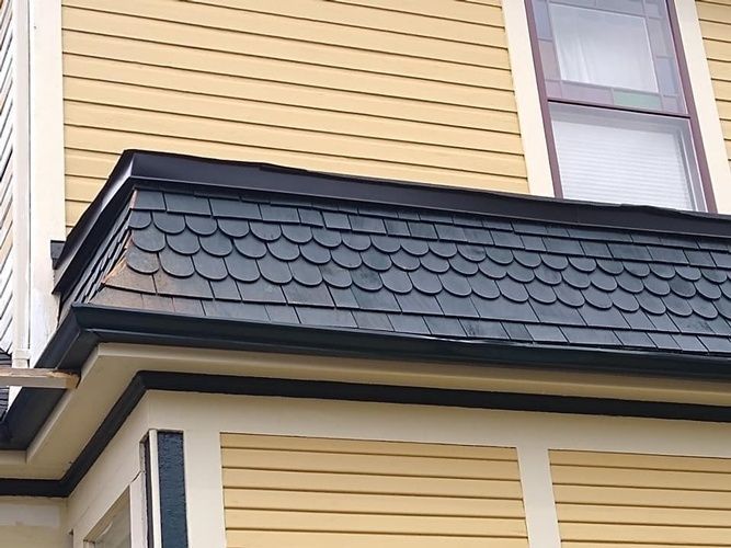 A yellow house with a black roof and a window