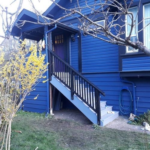 A blue house with stairs leading up to the front door