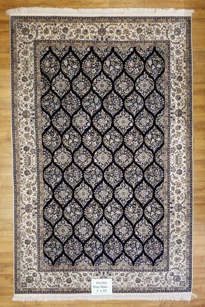 Black and ivory patterned oriental rug on a wooden floor, with floral border and repeating central design.