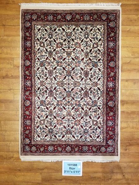 Red and cream floral patterned oriental rug on wood floor.