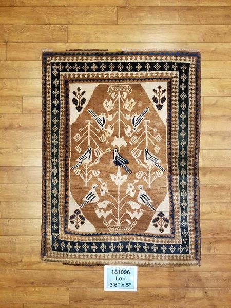 Tan, brown, and black rug with birds and floral patterns on a wooden floor.