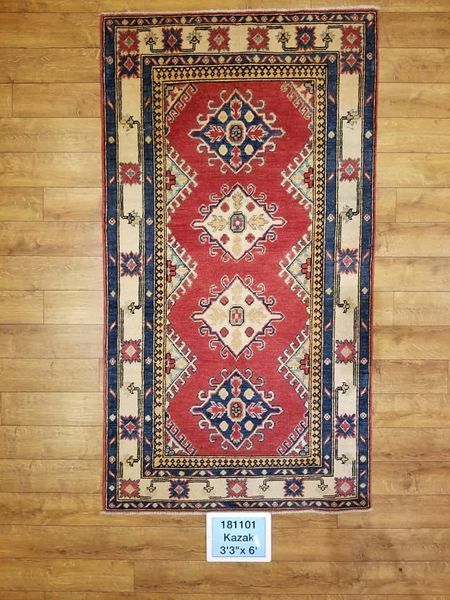 Red, blue, and cream patterned rug on a wooden floor.